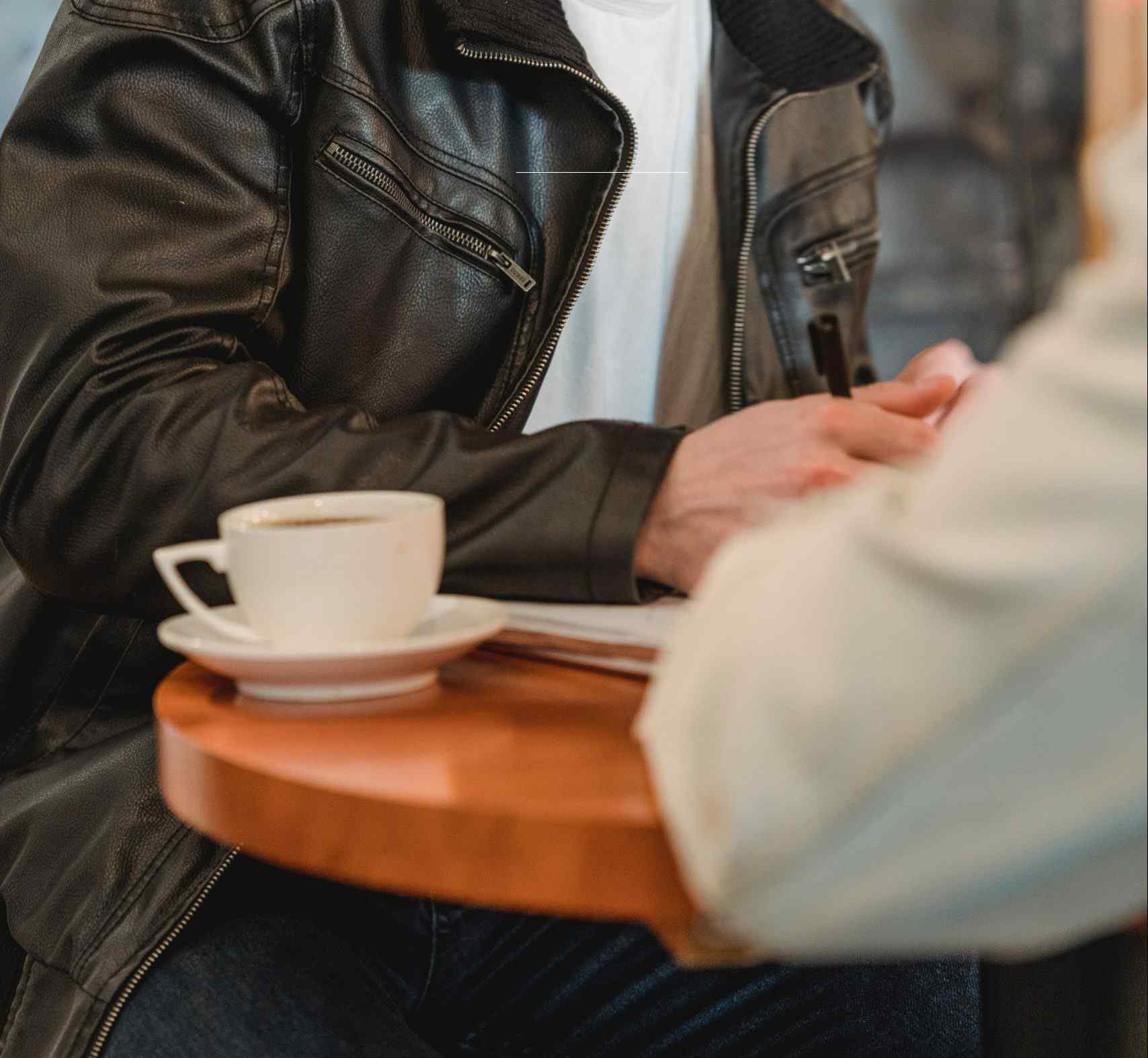 Black jacket man man in leather jacket signing docs and coffee on table